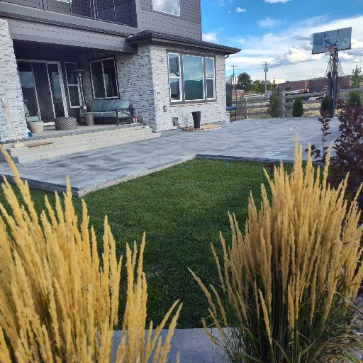 New stone paver patio with fresh lawn and ornamental grasses