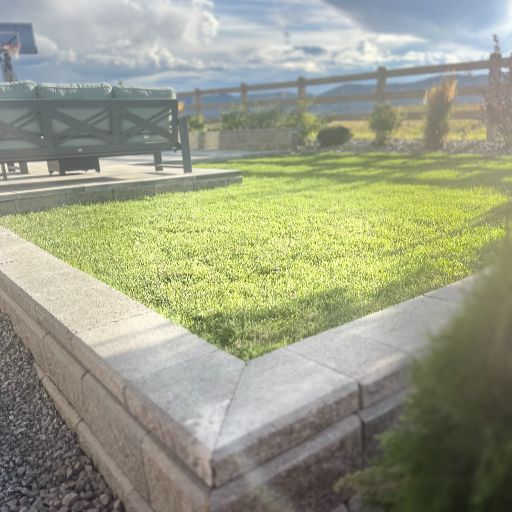 Completed retaining wall, pavers, and new sod in a Littleton, Colorado backyard