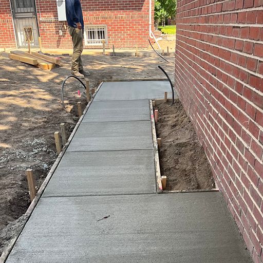 Freshly poured concrete side pathway along brick home — Denver, Colorado